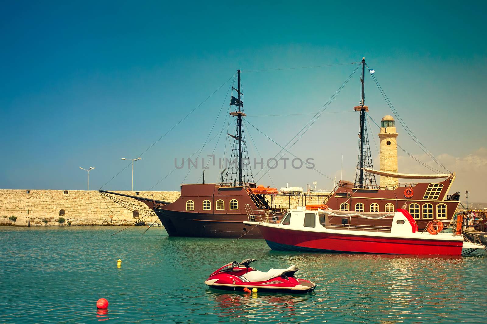 Views of the port , Rethymno city, Crete, Greece. There are multiple ships in the harbour, pier, lighthouse.