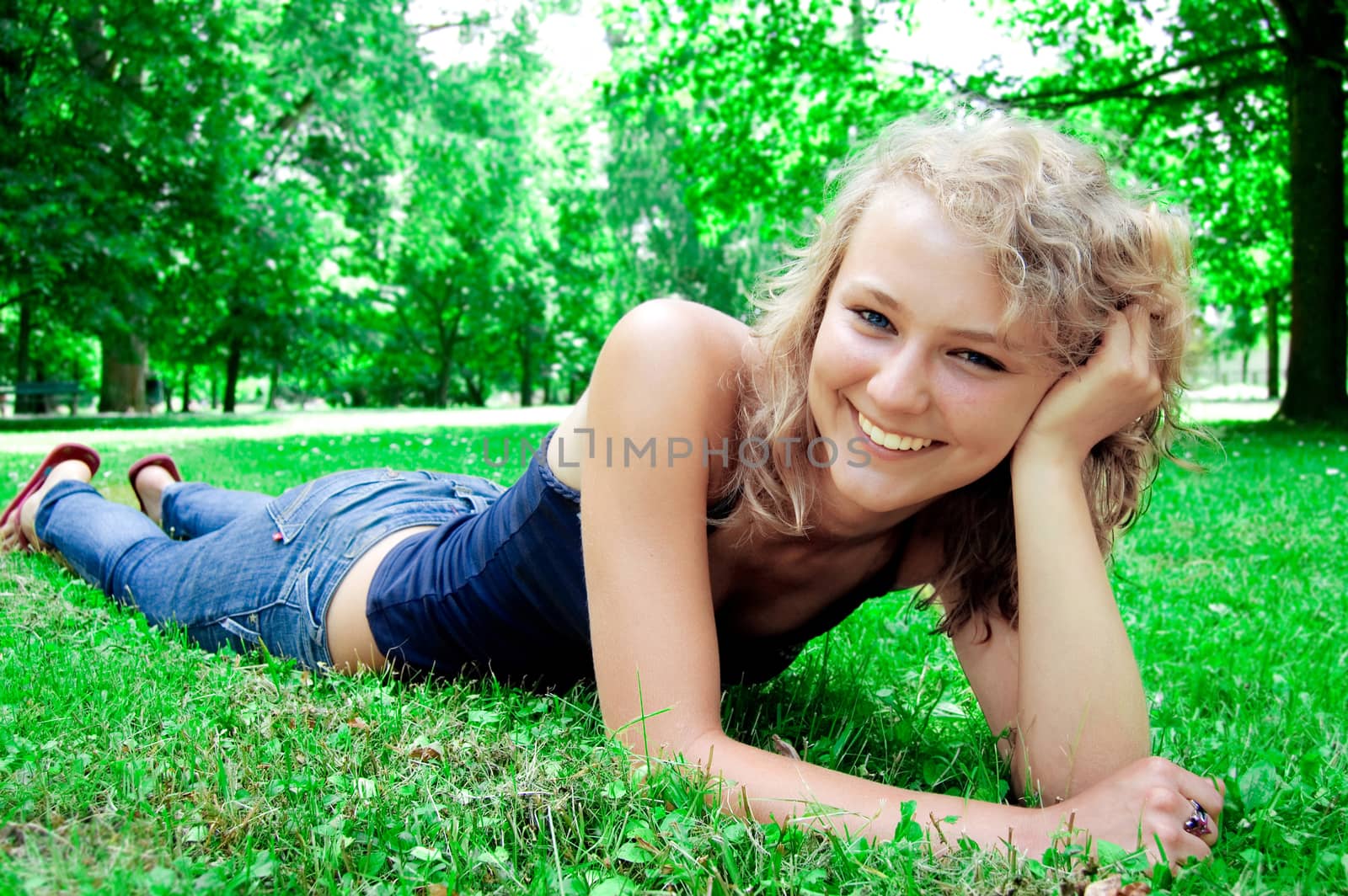 Young beautiful girl lies on the lawn and smiles.