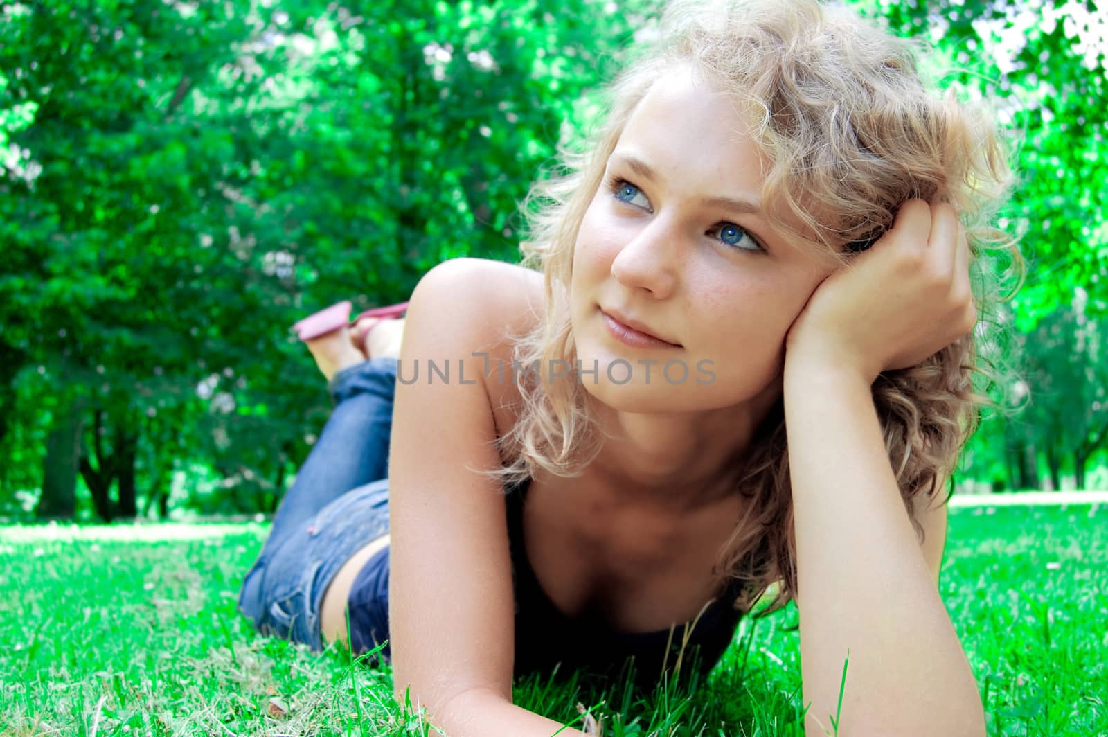 Young beautiful girl lies on the lawn and thinking about the future.