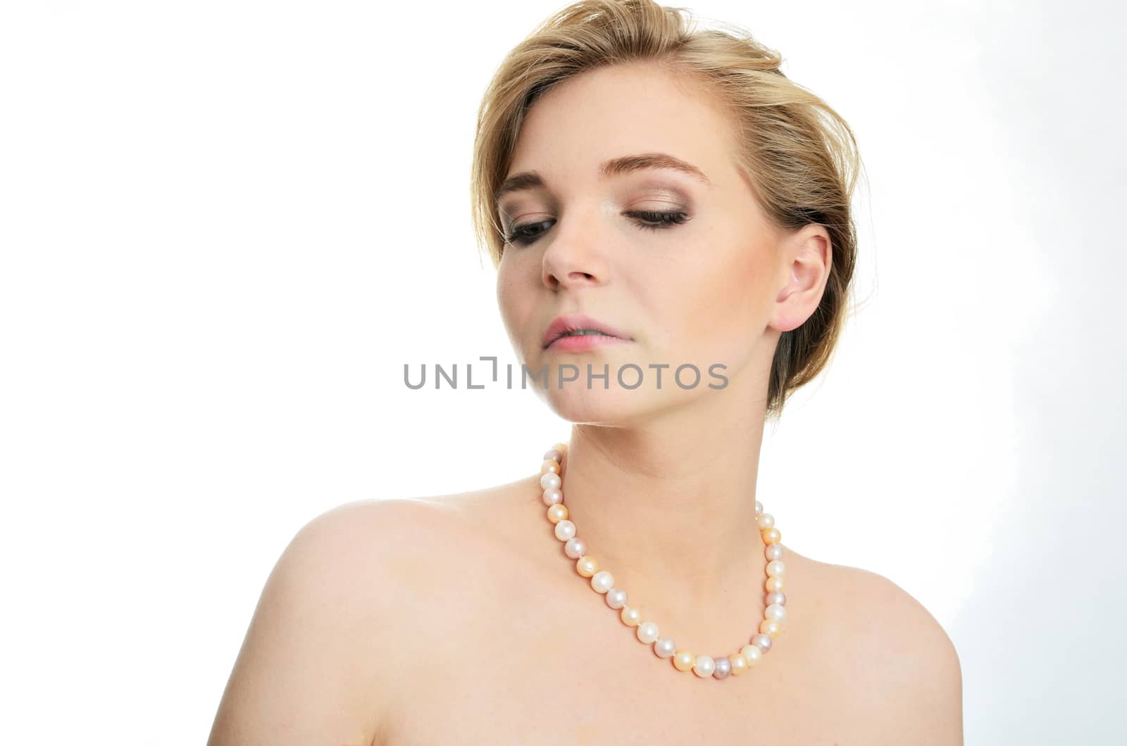 Beautiful female model with pearls on her neck. Portrait of young girl with soft and kind face expression.