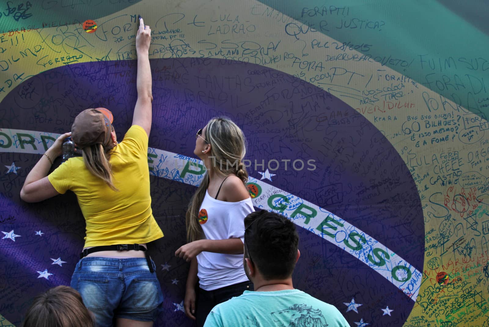 SAO PAULO, BRAZIL August 16, 2015: Two unidentified women  signing a large brazilian flag in the protest against federal government corruption in Sao Paulo Brazil.