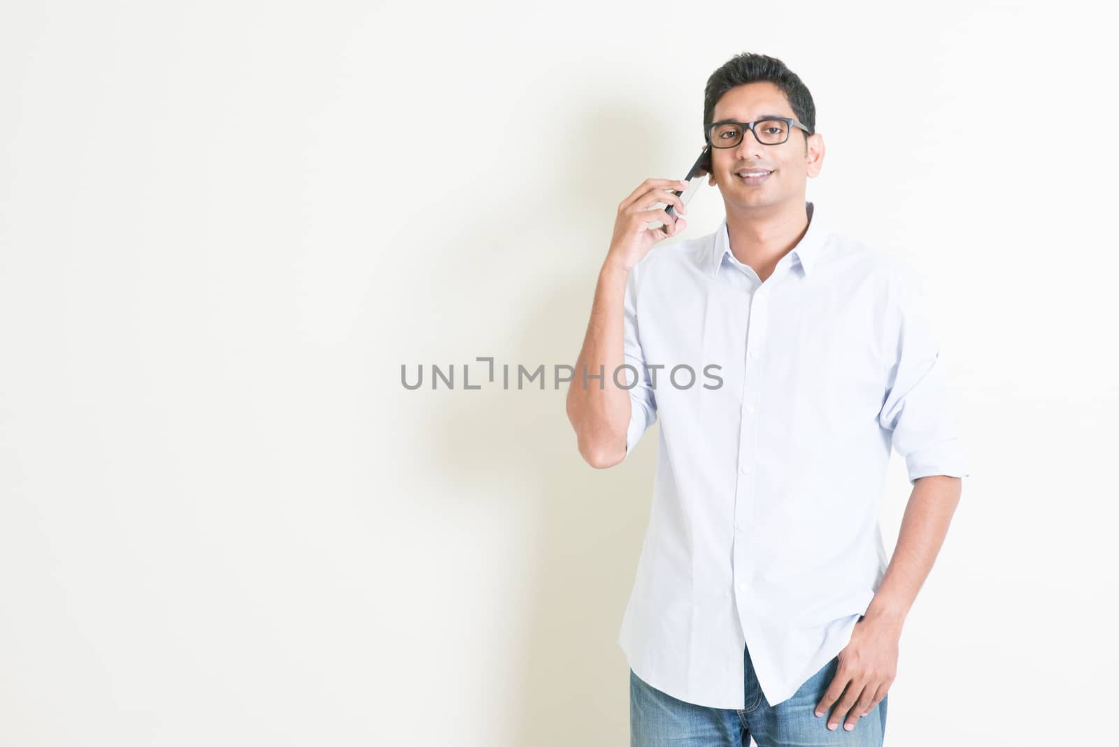 Casual business Indian male talking on smartphone by szefei
