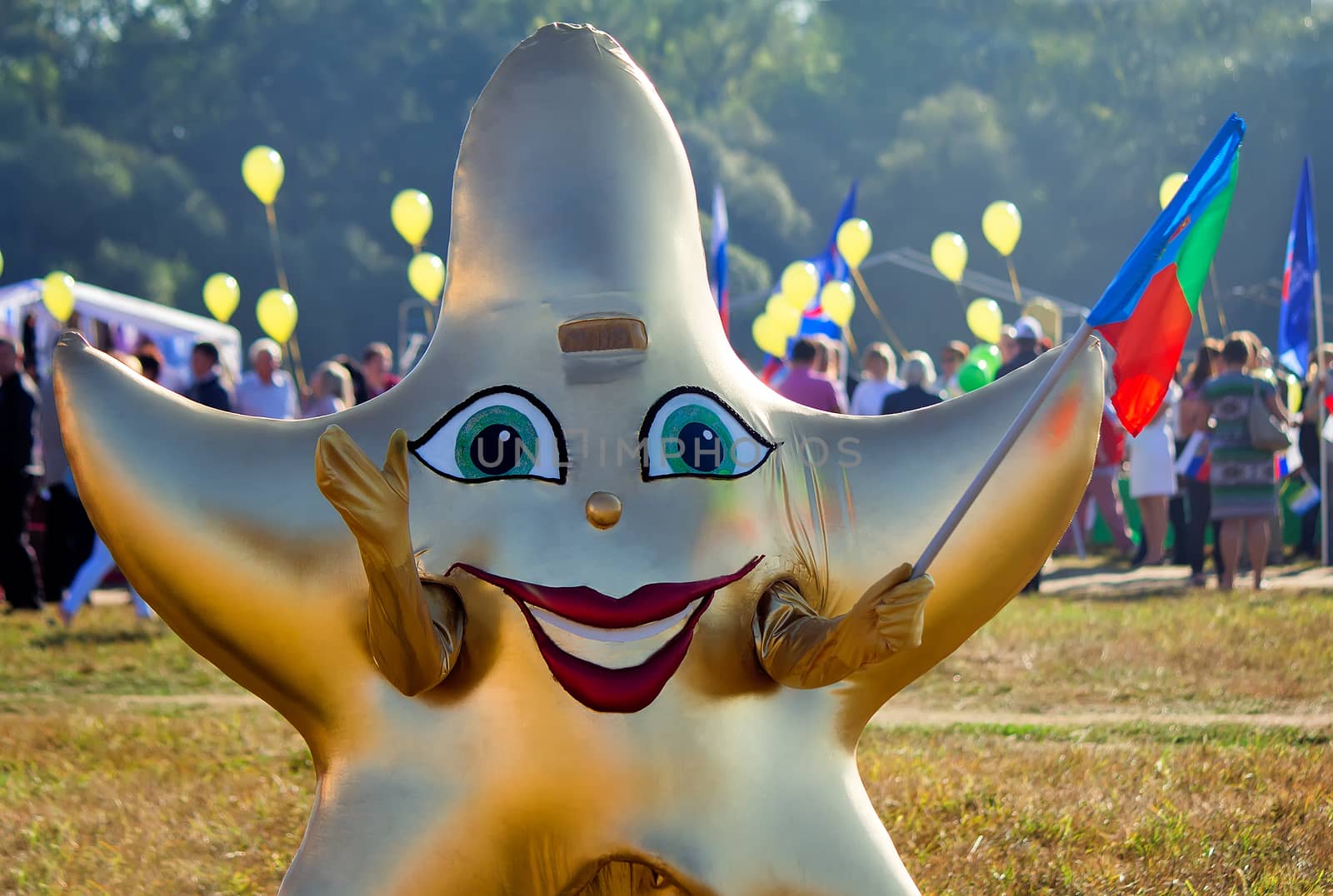 Depicts a man in a funny costume in the form of a star with a flag in his hand at the festival.