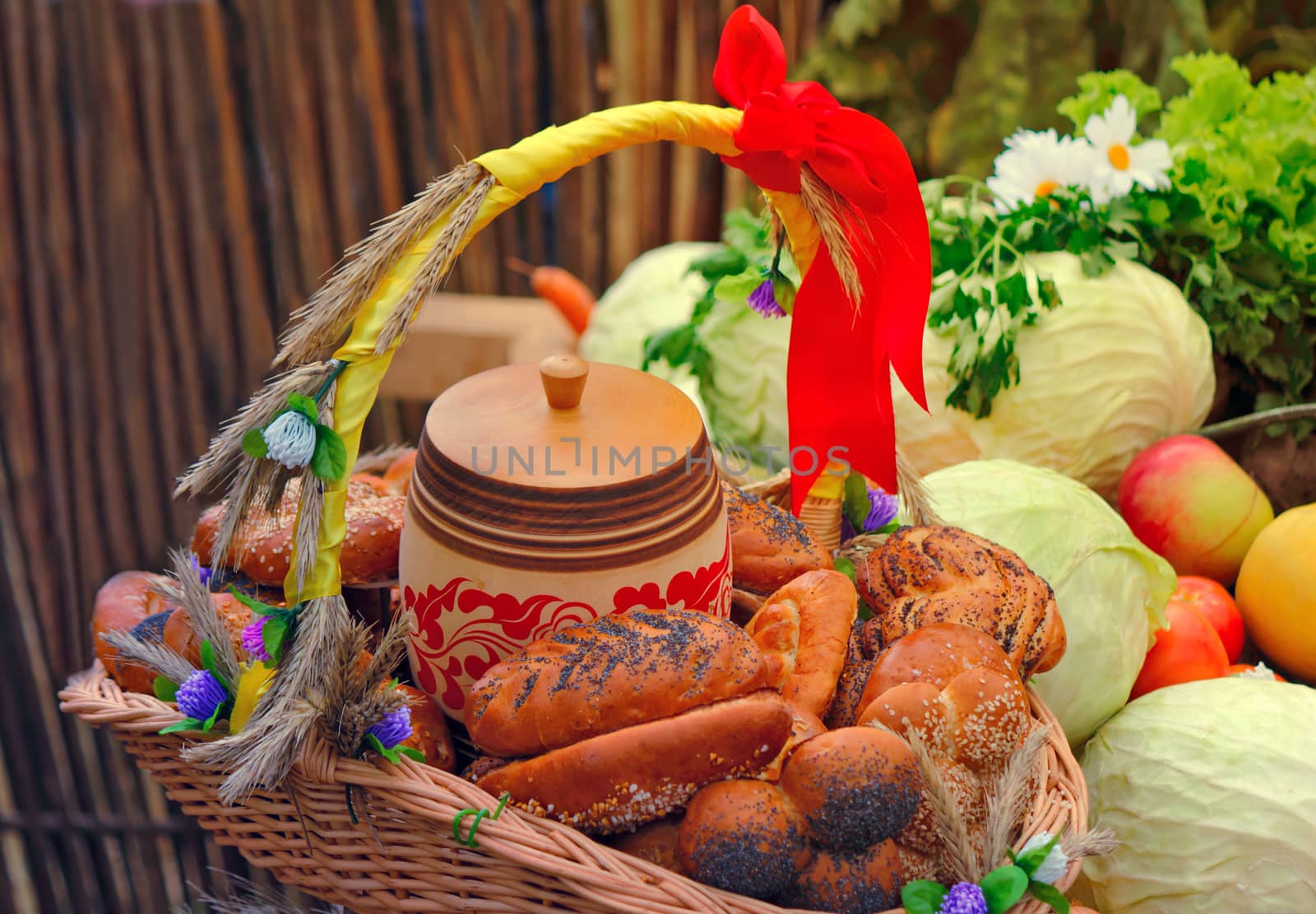 Beautifully decorated with ribbons, a basket with bread, is next with vegetables and fruit.
