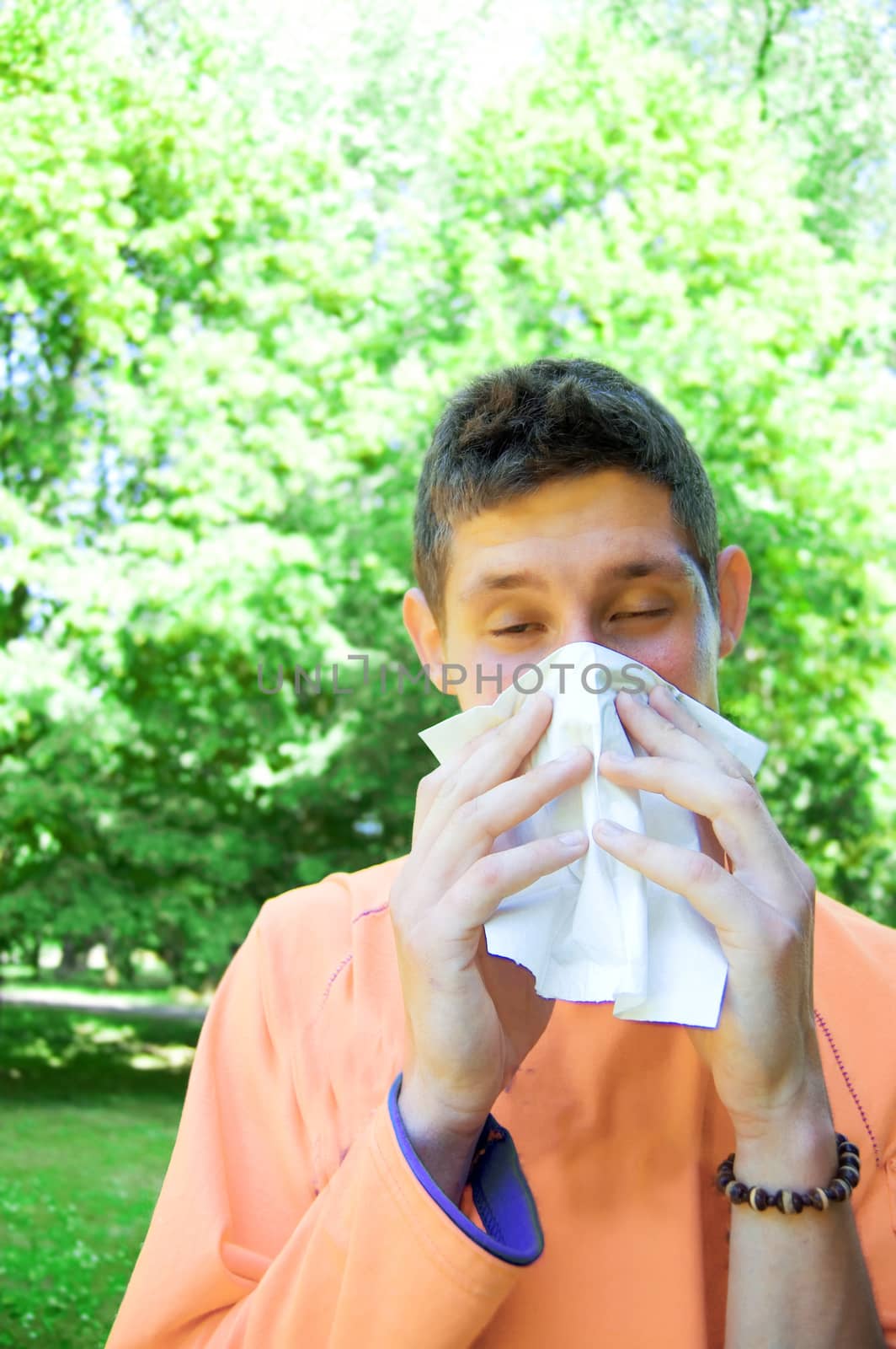 Young man blowing his nose because he has allergies.