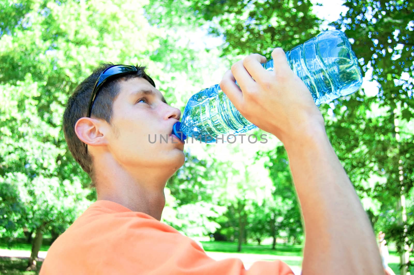Young man drinking water in heat.