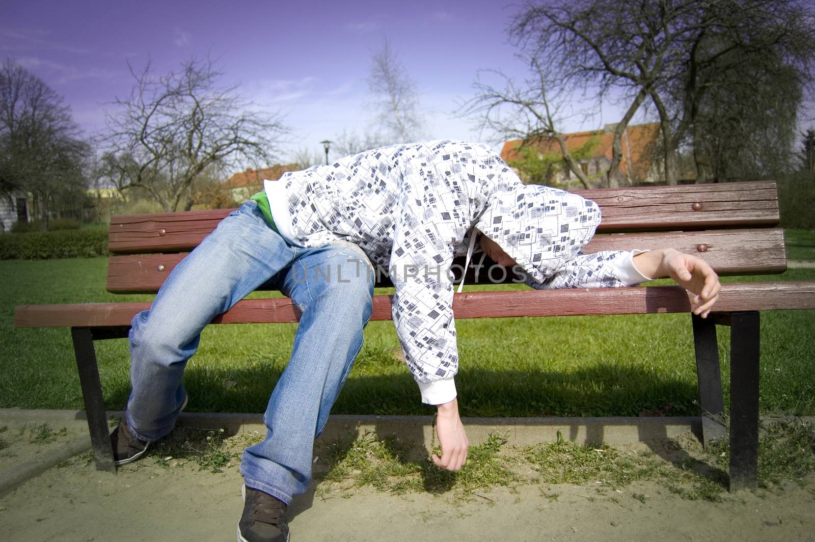 A drunken man lying on a park bench.