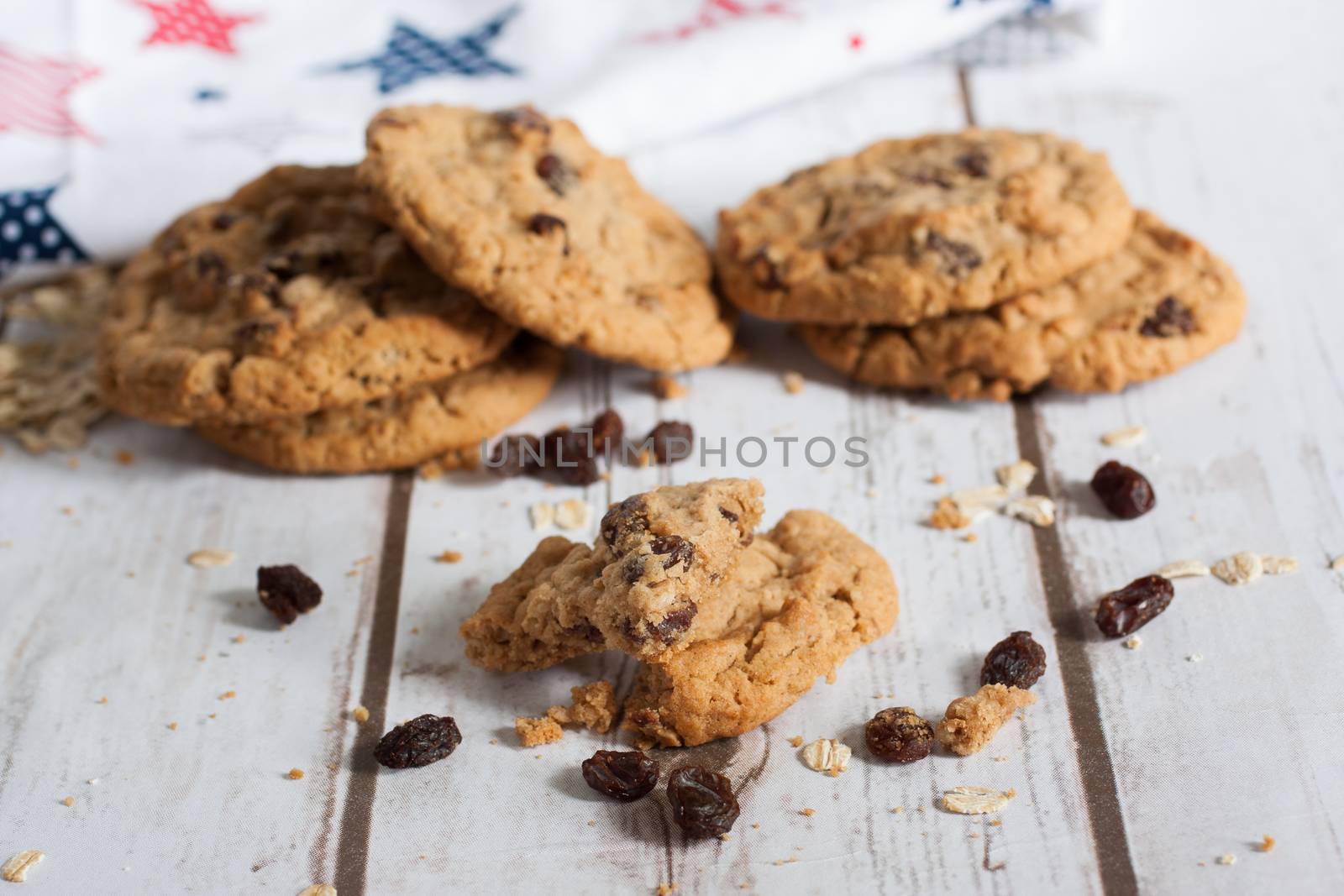 Oatmeal raisin cookies on a table with a printed tea towel in the background.