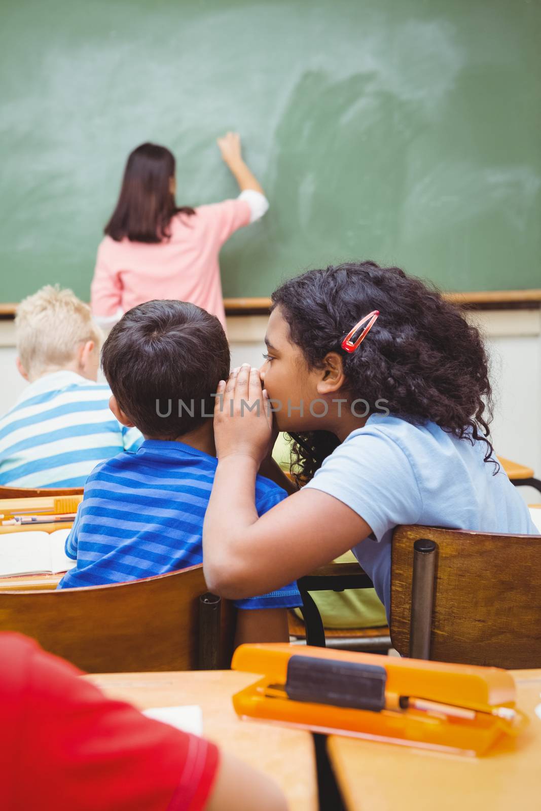 Student whispering into another students ear by Wavebreakmedia