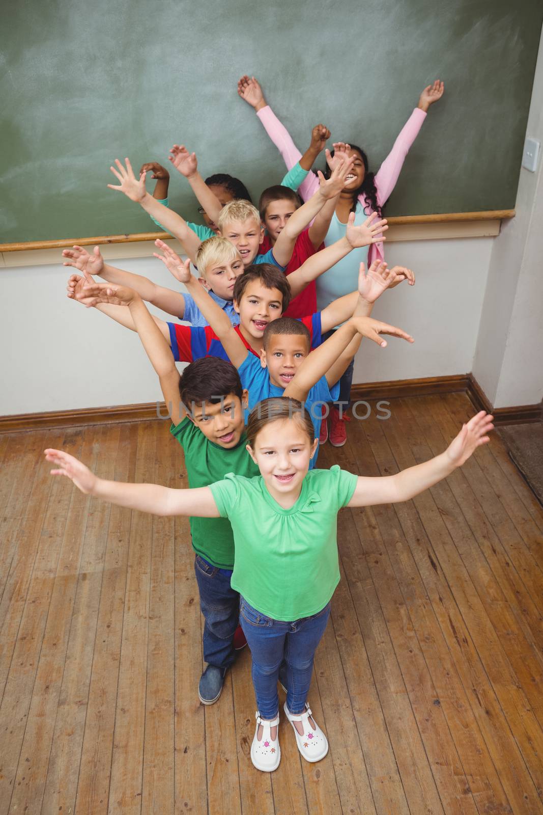 Students with arms raised together by Wavebreakmedia