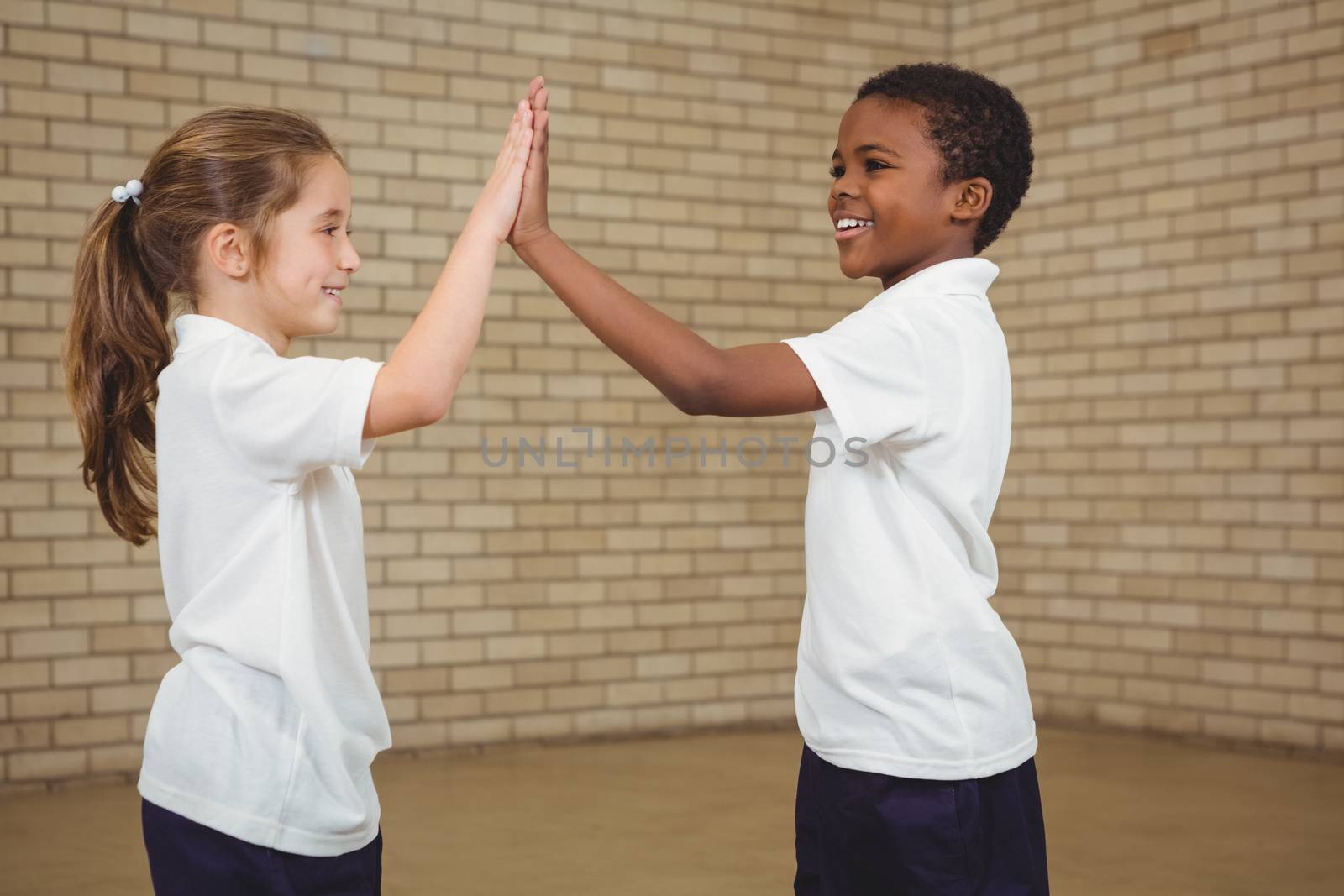 Happy pupils giving each other a high five at the elementary school