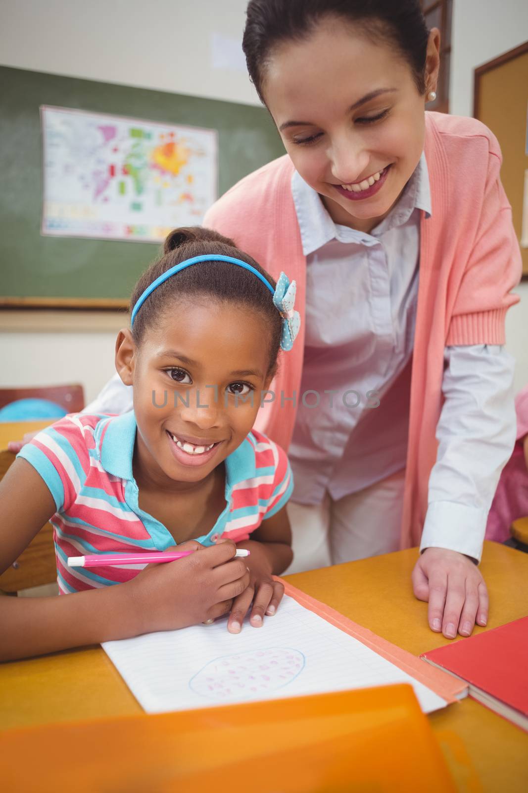 Pupil and teacher at desk in classroom at the elementary school