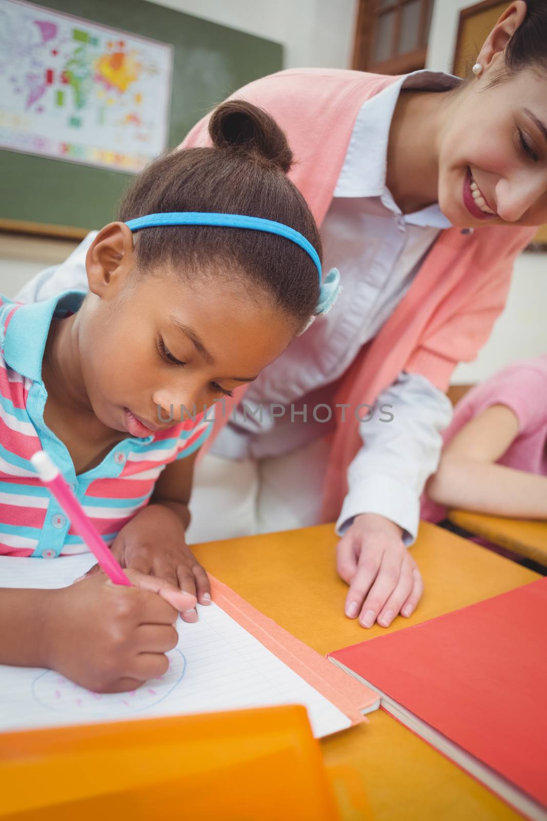 Pupil and teacher at desk in classroom at the elementary school