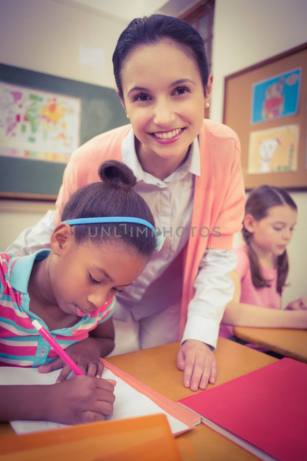 Pupil and teacher at desk in classroom at the elementary school