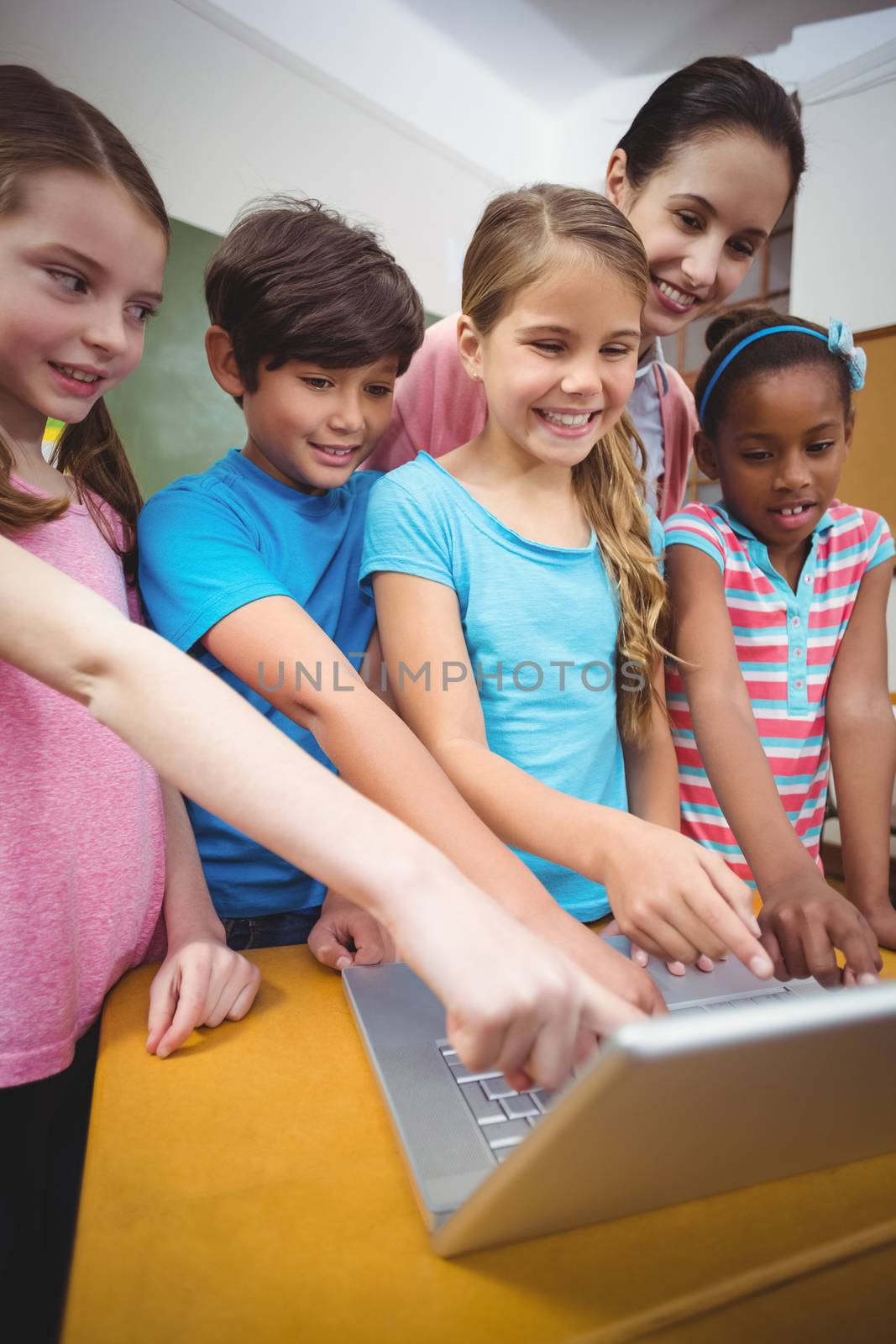 Teacher and pupils looking at laptop at the elementary school