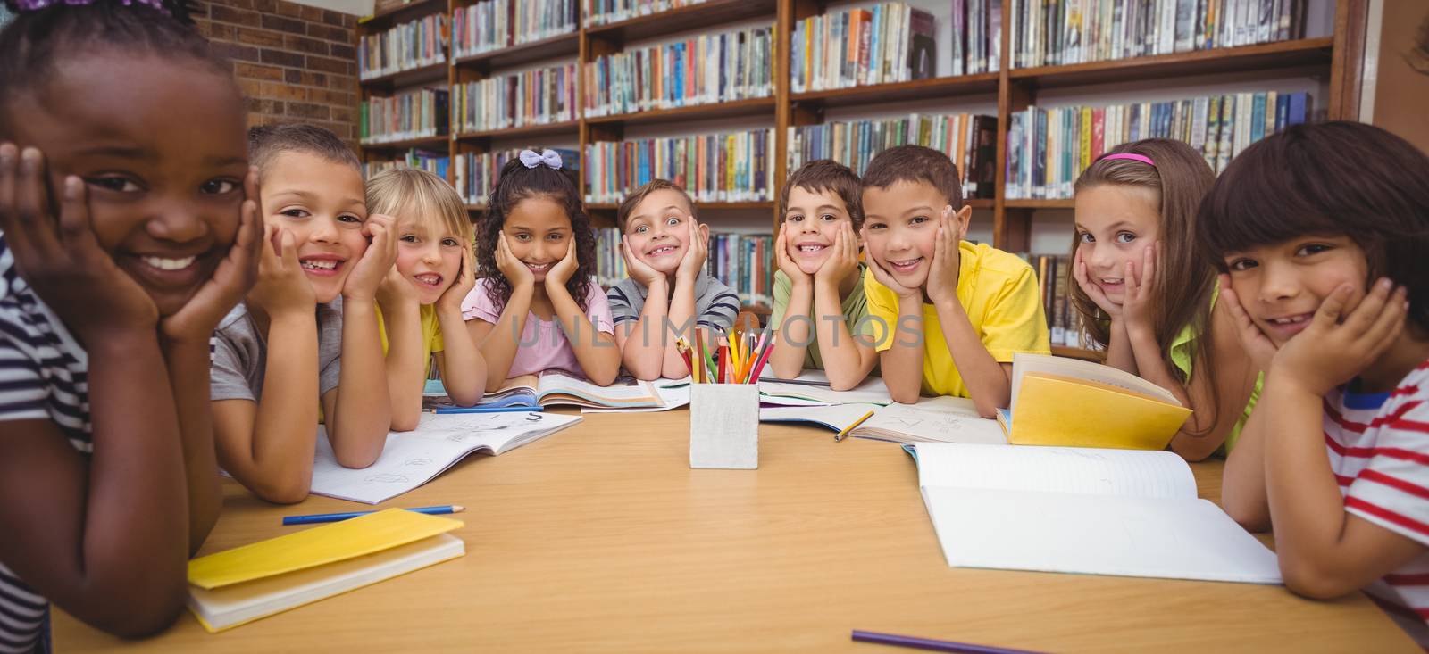 Pupils working together at desk in library by Wavebreakmedia