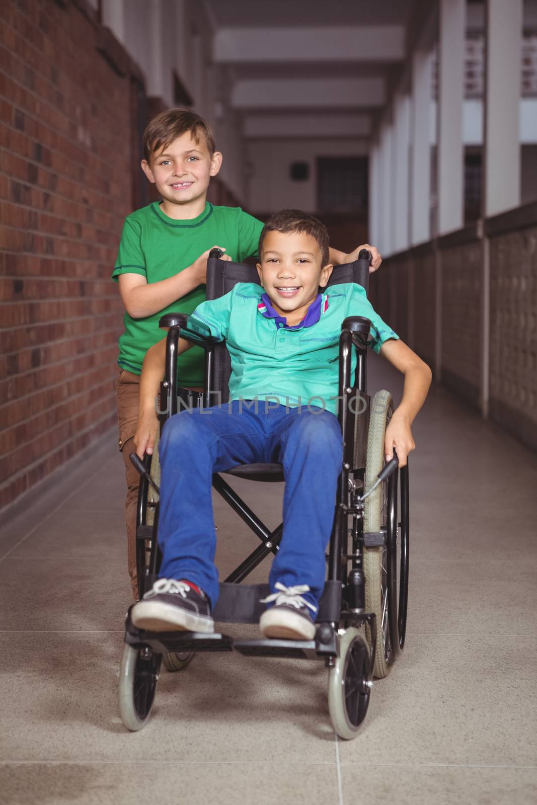 Smiling student in a wheelchair and friend beside him on the elementary school grounds