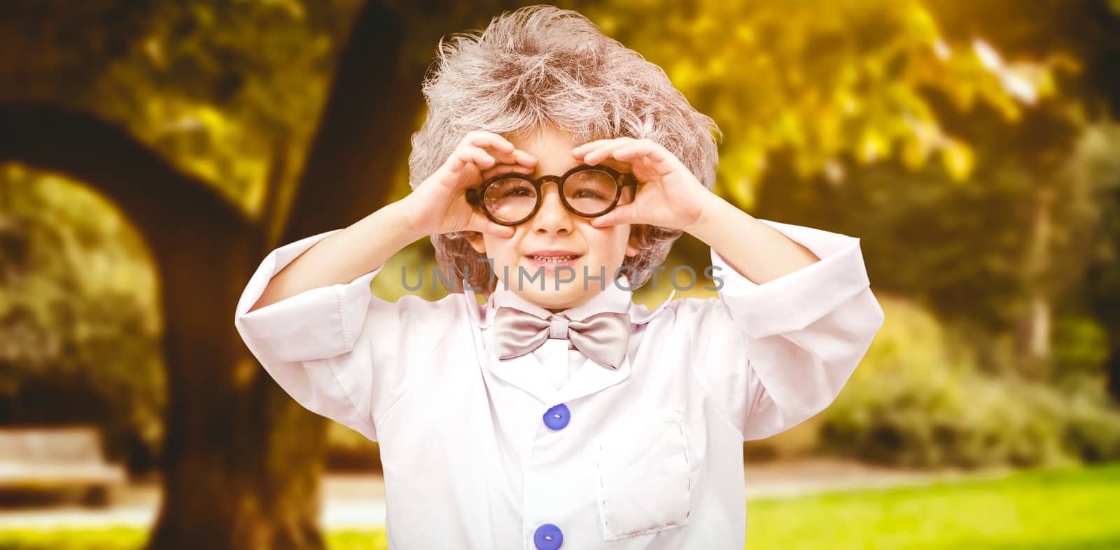 Cute pupil in lab coat  against trees and meadow in the park