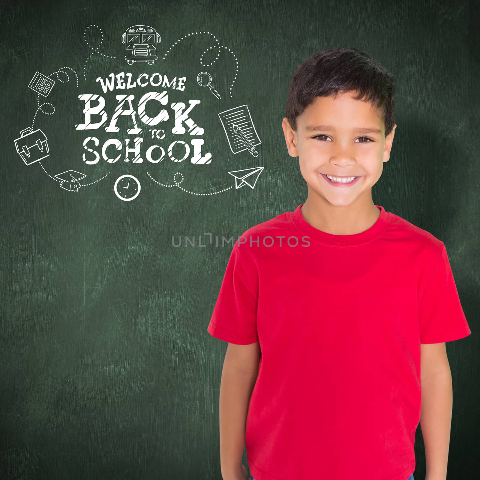 Cute boy smiling at camera against green chalkboard