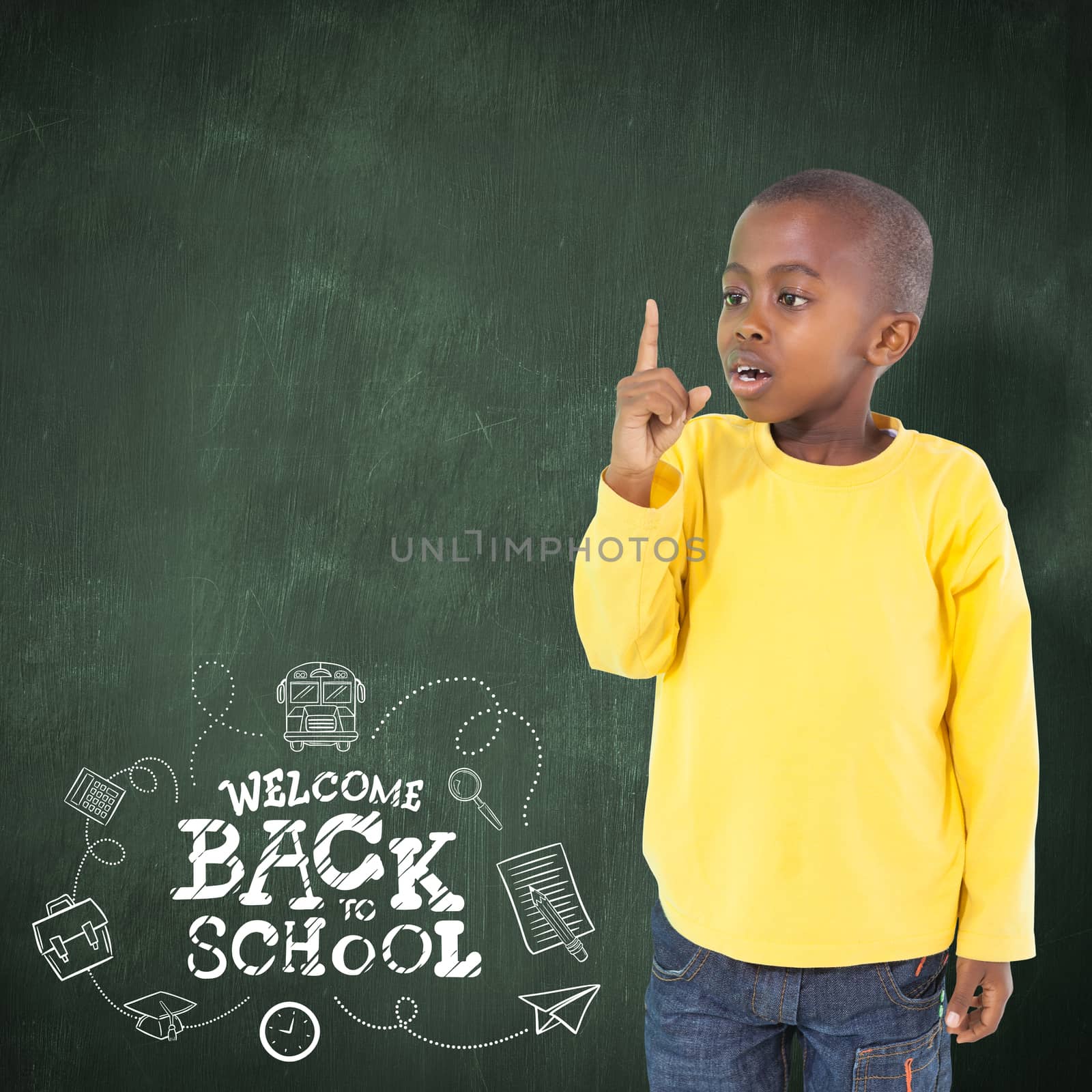 Cute boy pointing against green chalkboard
