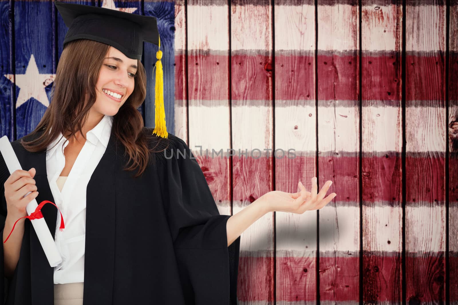 Composite image of a woman holding her hand out with a degree in her other hand as she smiles by Wavebreakmedia