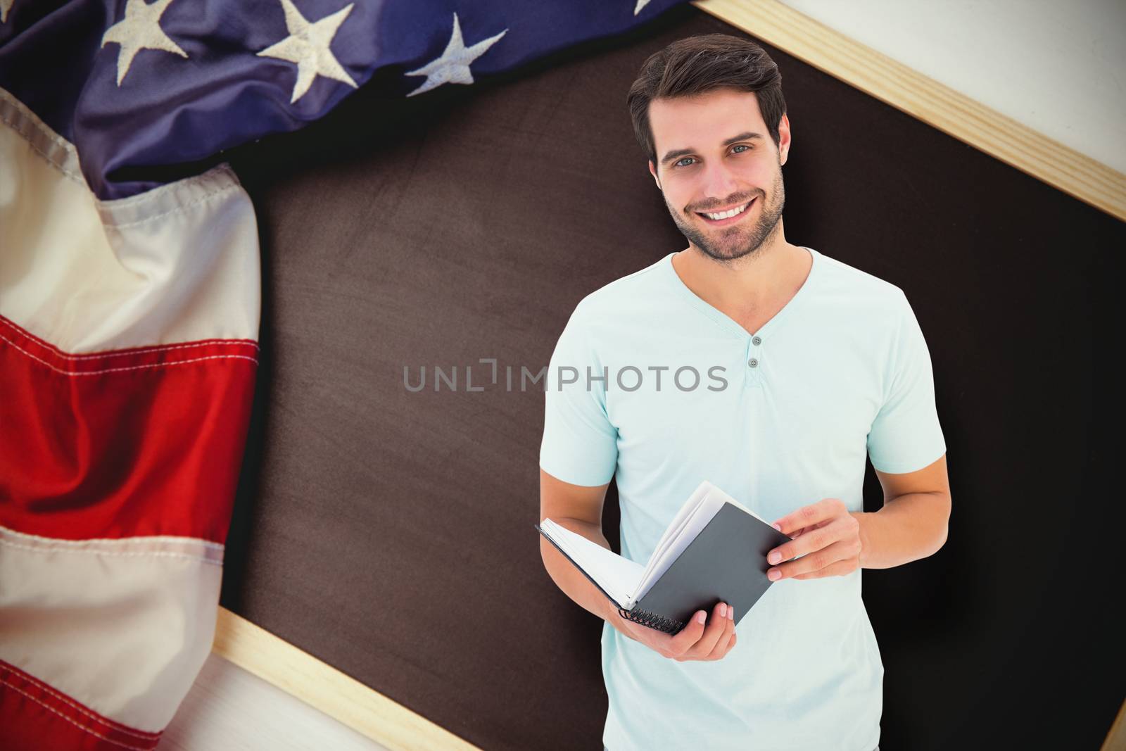 Student holding book against american flag on chalkboard