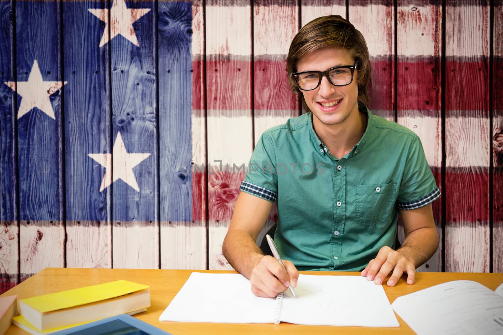 Student sitting in library writing against composite image of usa national flag