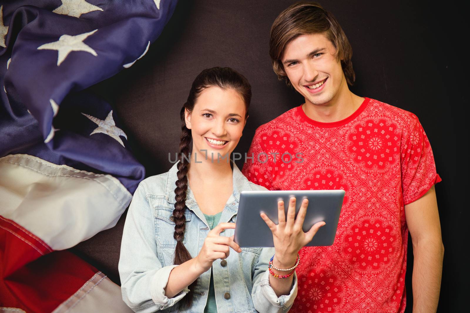 Smiling classmates with tablet pc against american flag on chalkboard