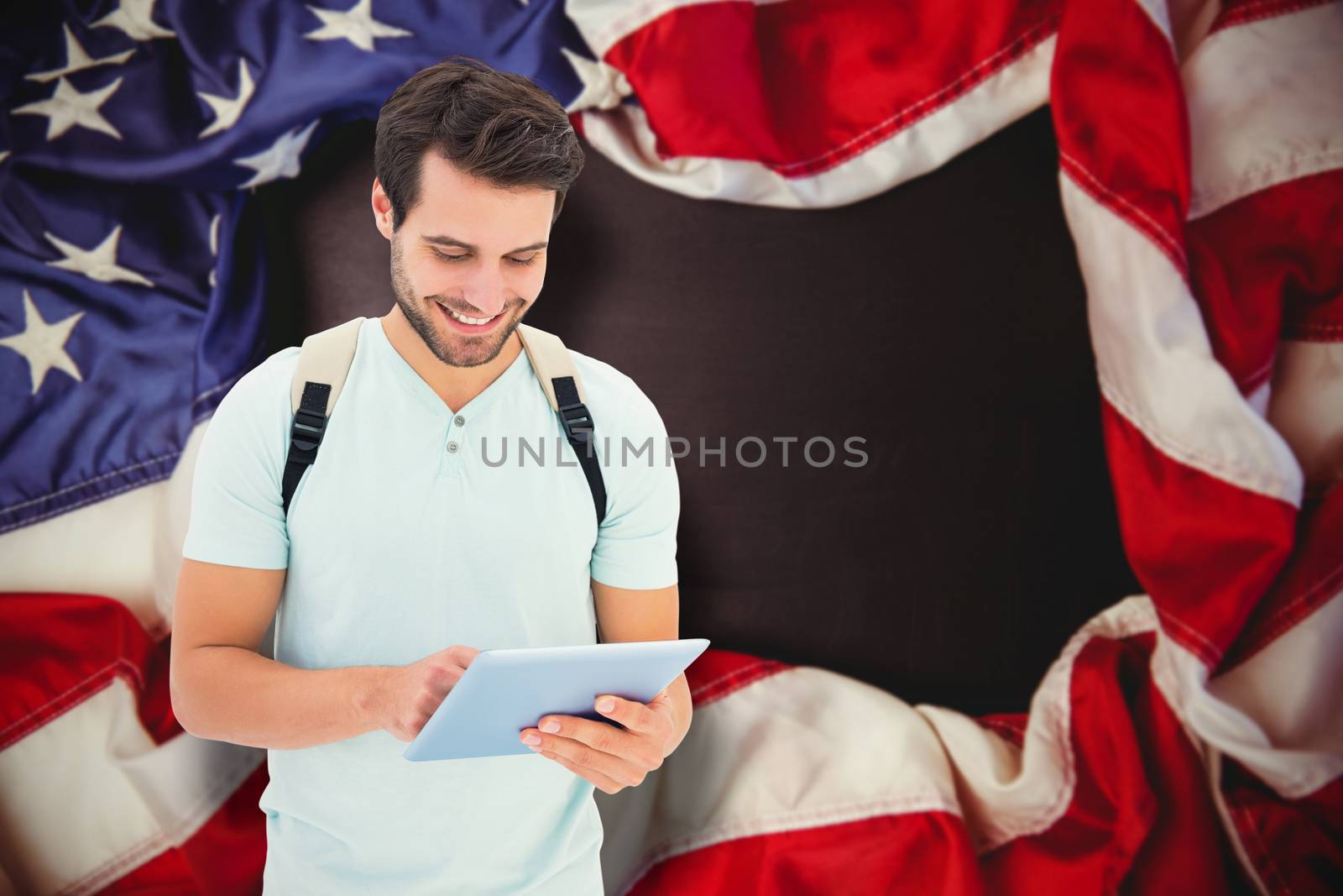Student using tablet pc against american flag on chalkboard