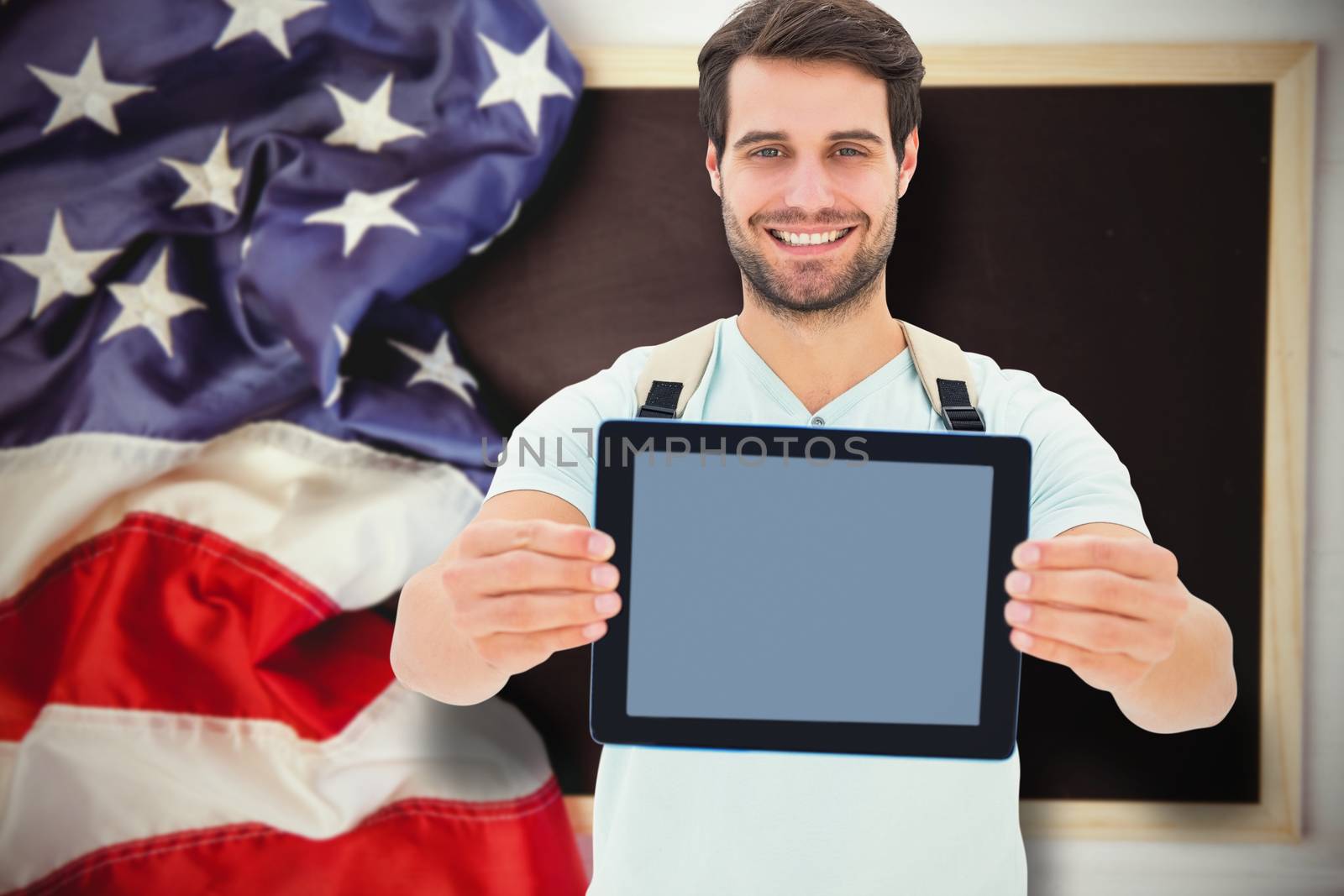 Student showing tablet against american flag on chalkboard