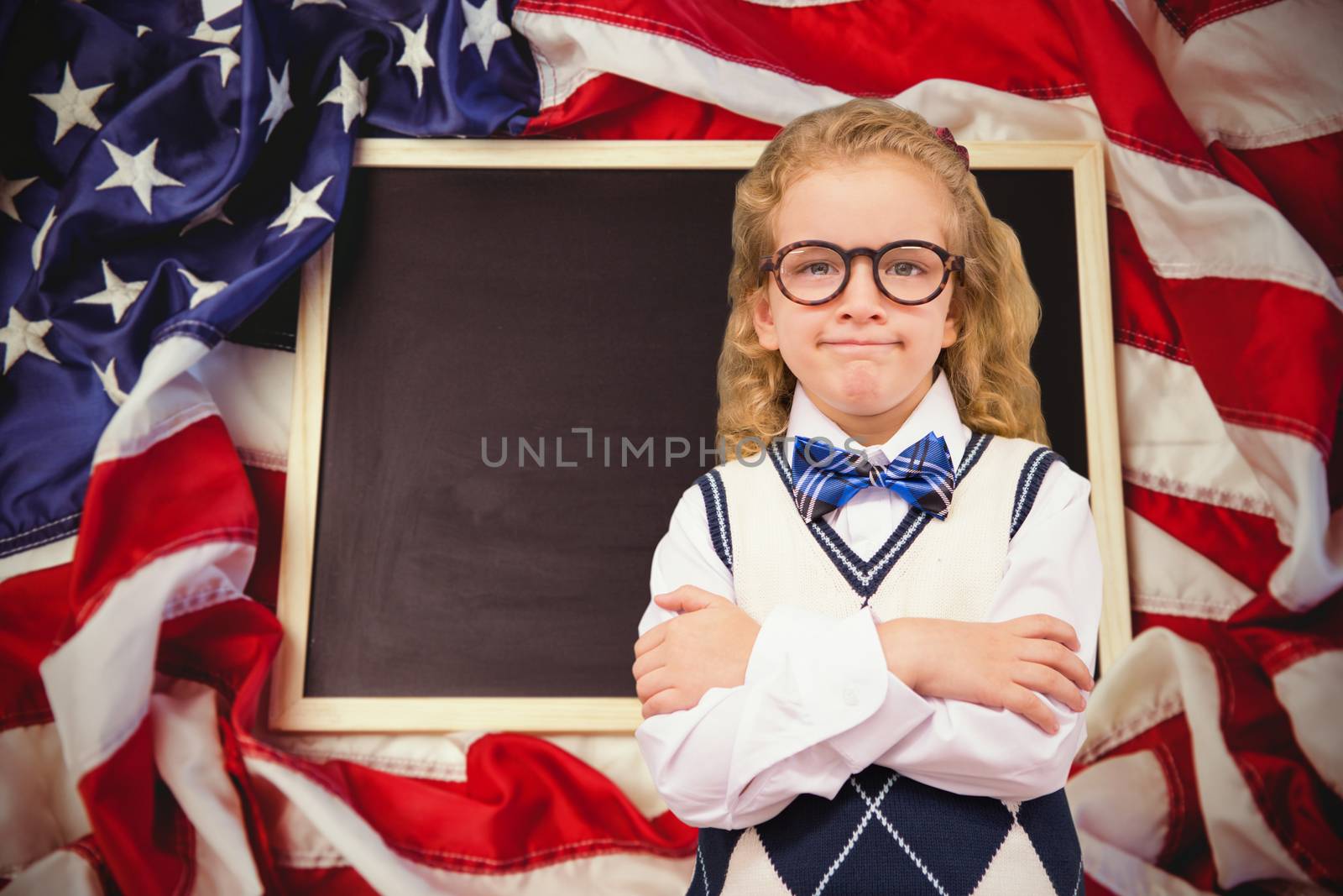 Cute pupil with arms crossed against american flag on chalkboard