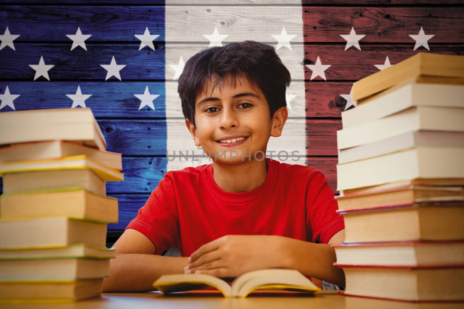 Portrait of boy reading book at desk against composite image of usa national flag