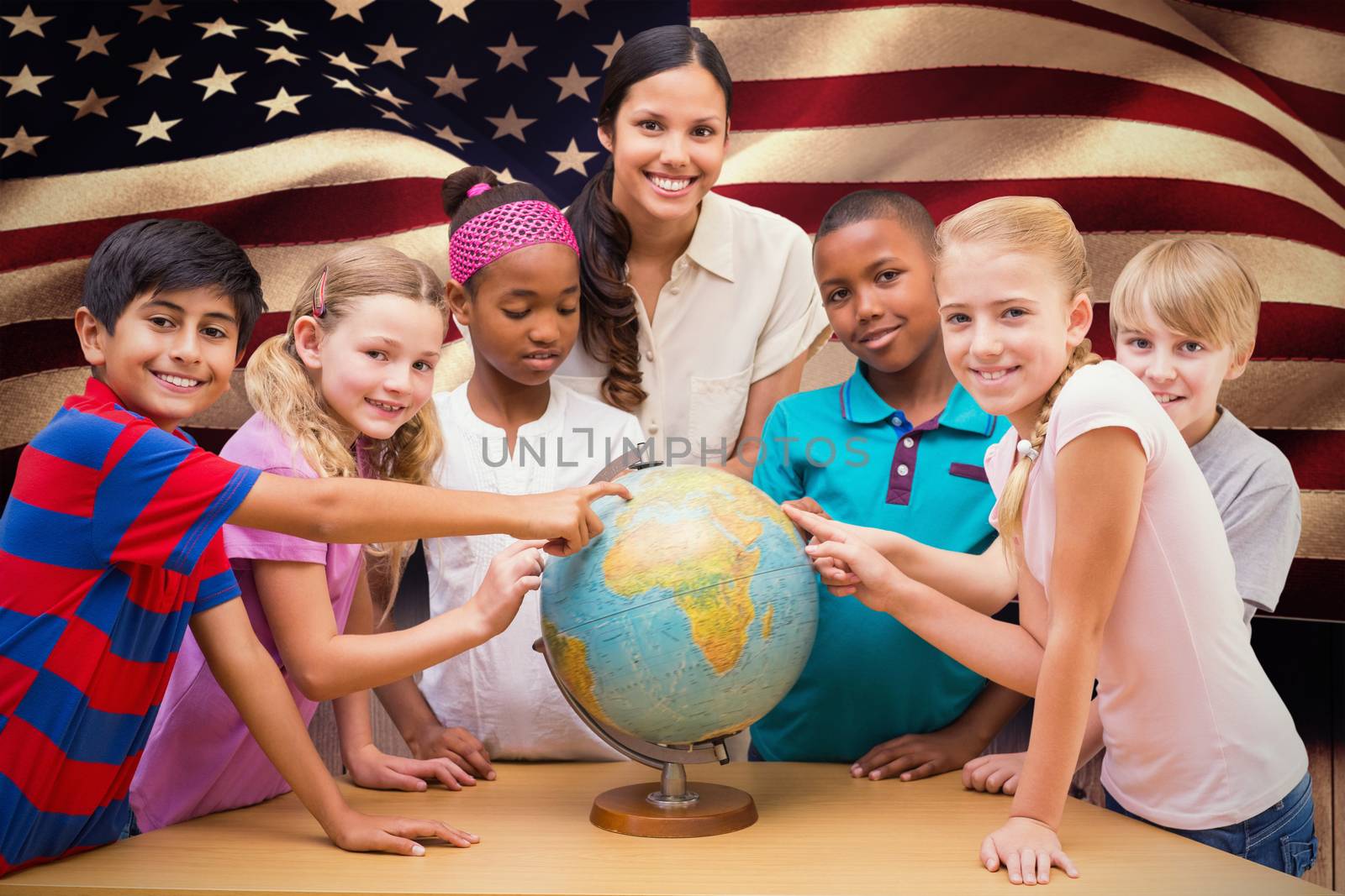 Cute pupils and teacher looking at globe in library against composite image of digitally generated united states national flag