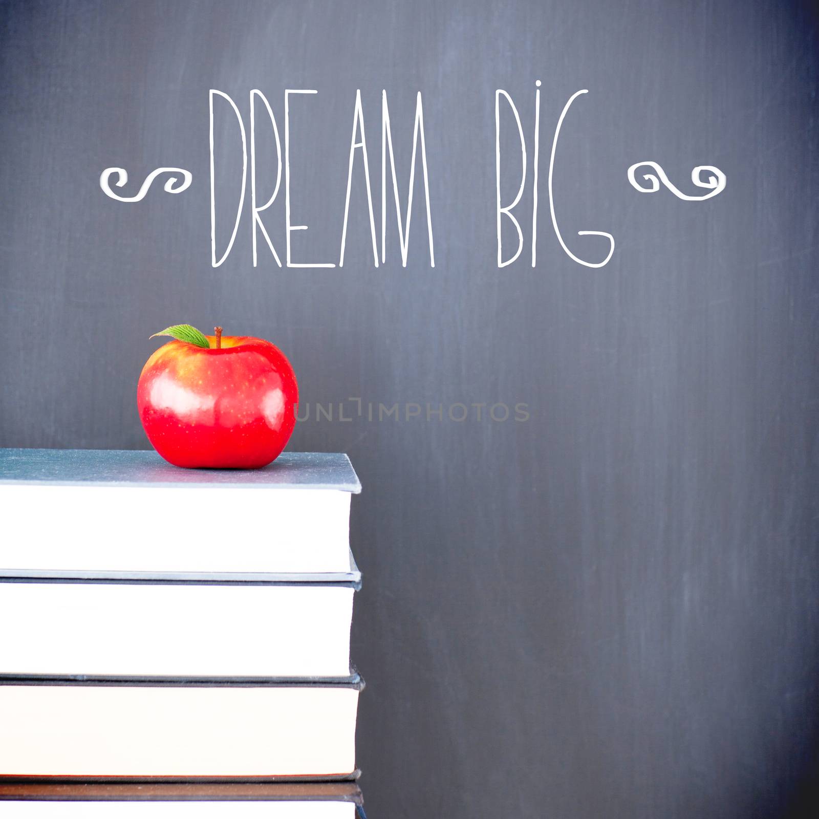 The word dream big against red apple in front of blackboard on books