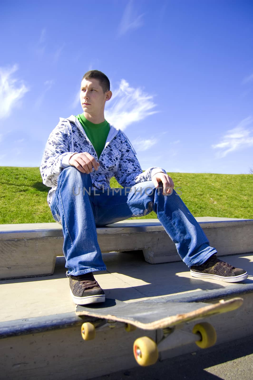 Skateboarder conceptual image. Teenage skateboarder sits in skatepark.