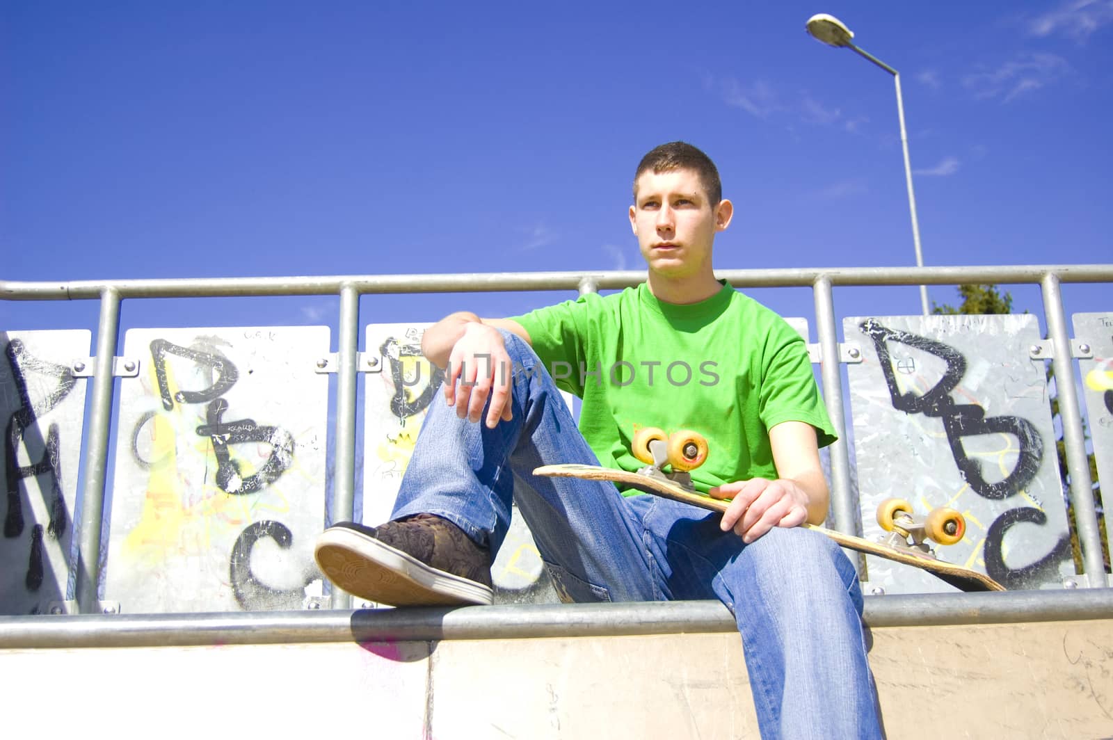 Teenage skateboarder conceptual image. Teenage skateboarder sits in skate-park.
