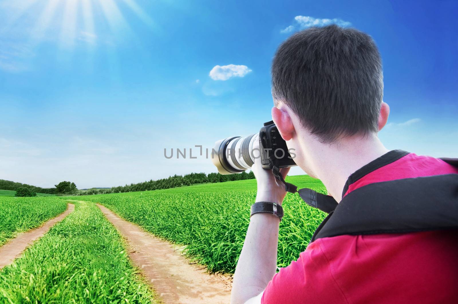 Photographer taking a picture of green field at summer.