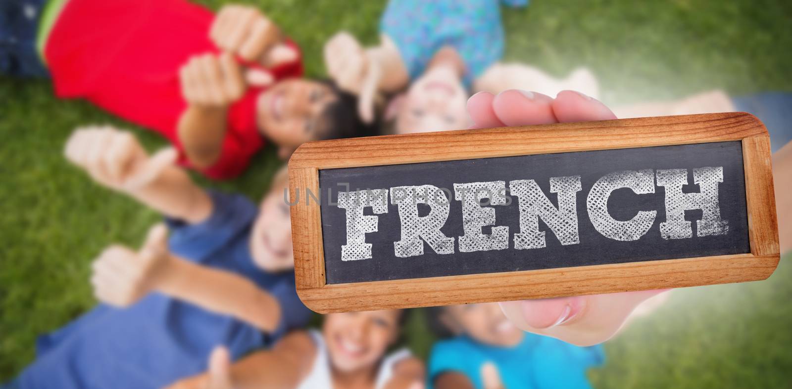 The word french and hand showing chalkboard against happy friends playing in the park