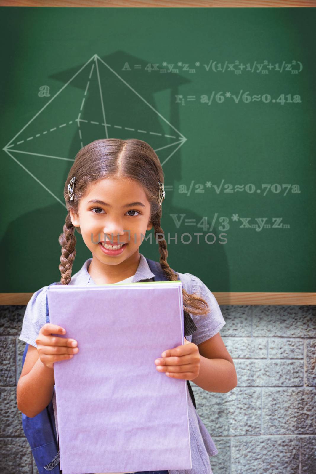 Cute pupil smiling at camera holding notepad  against green