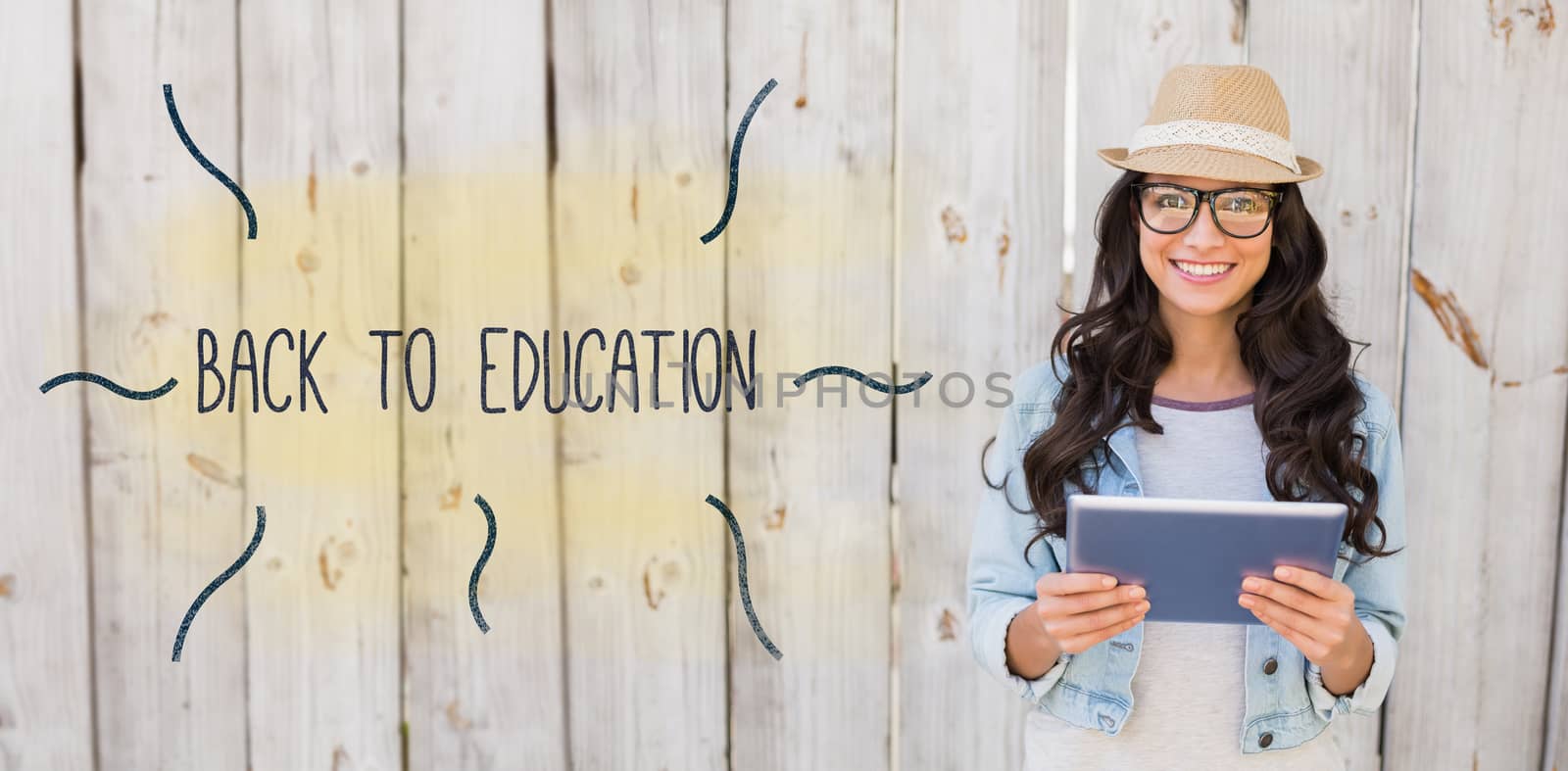 Back to education against pretty hipster smiling at camera holding tablet by Wavebreakmedia