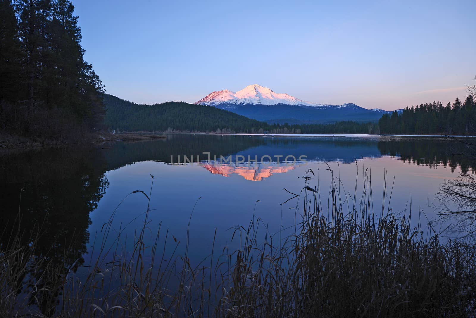 a reflection of mount shasta over a lake during sunset