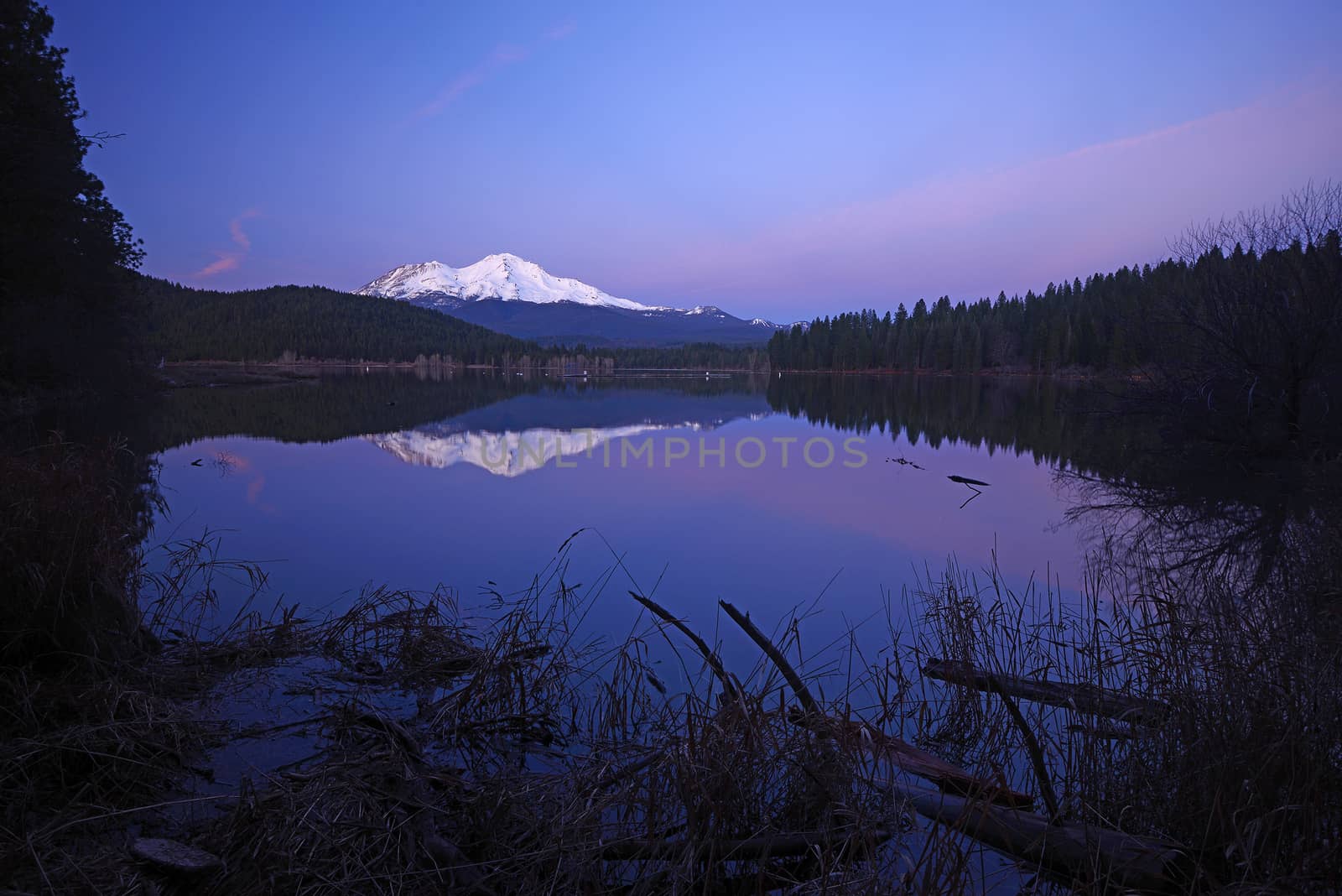 a reflection of mount shasta over a lake during sunset