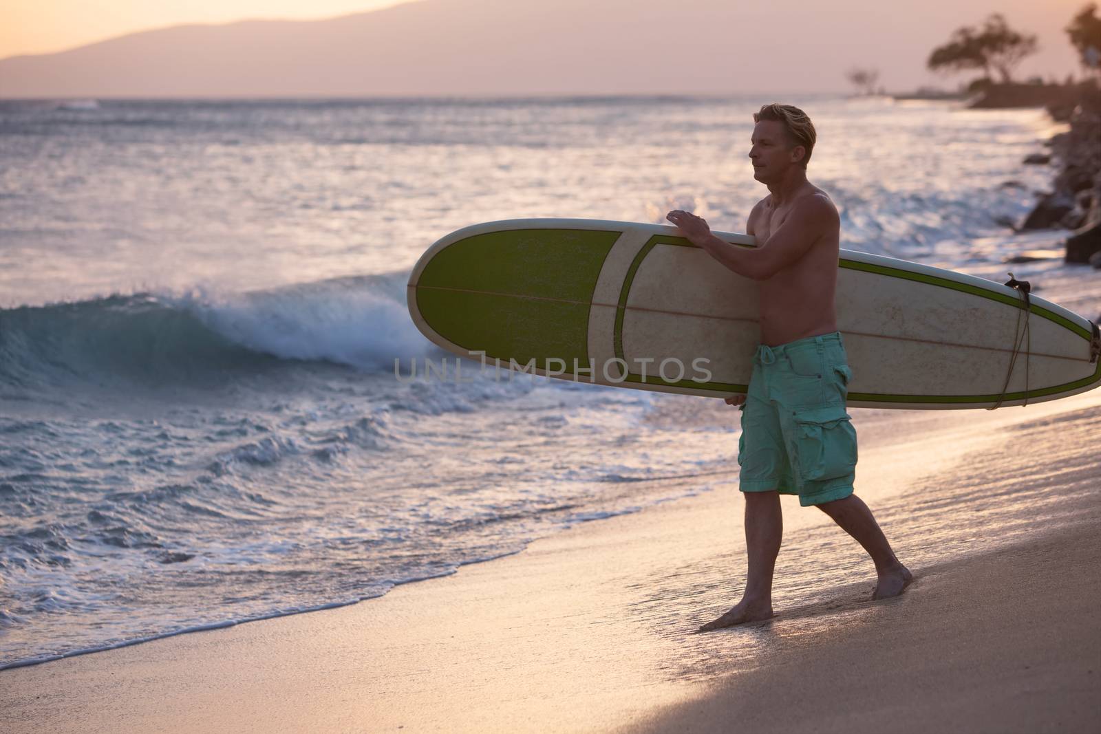 Adult surfer walking surfboard toward ocean waves