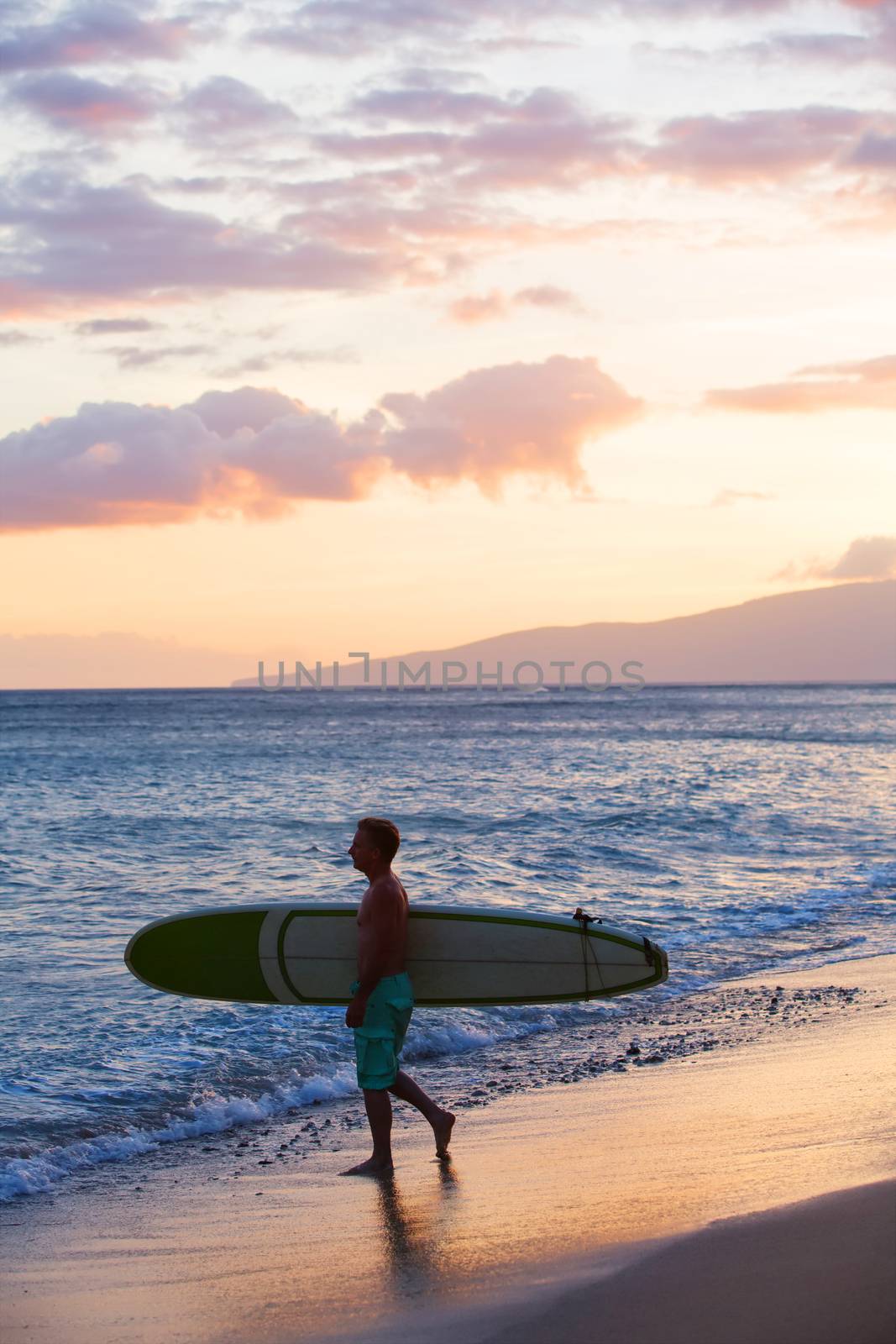 Ocean beach scene with man carrying surfboard to water