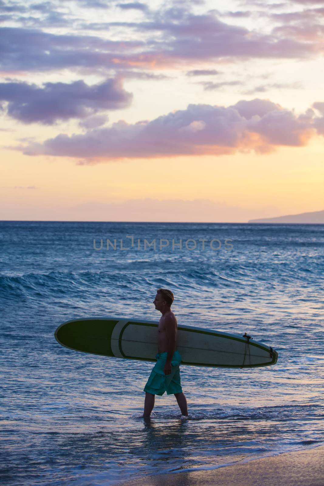 Single surfer carrying his surfboard into the ocean