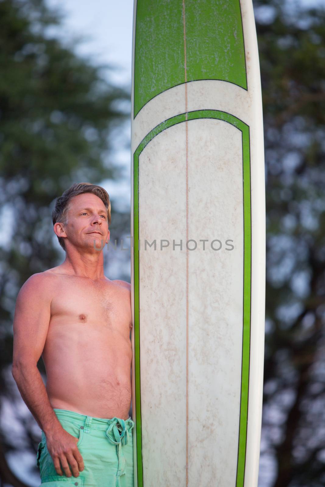 Single confident male surfer holding surfboard outdoors