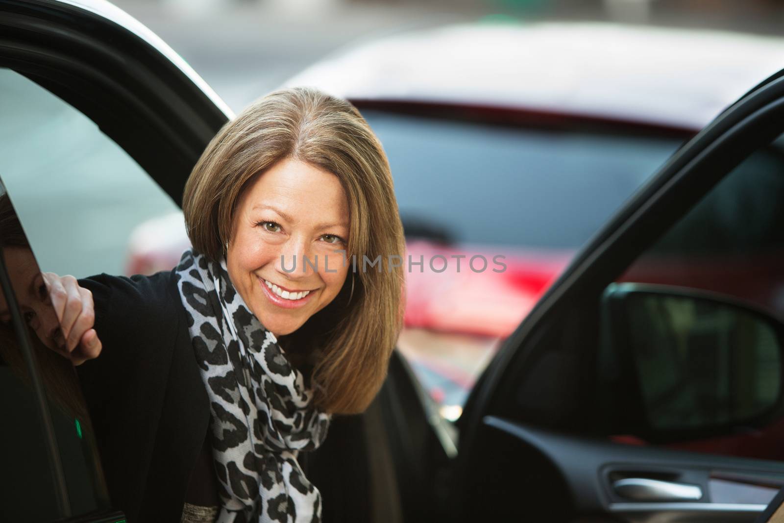 Beautiful smiling adult business woman in car with open door