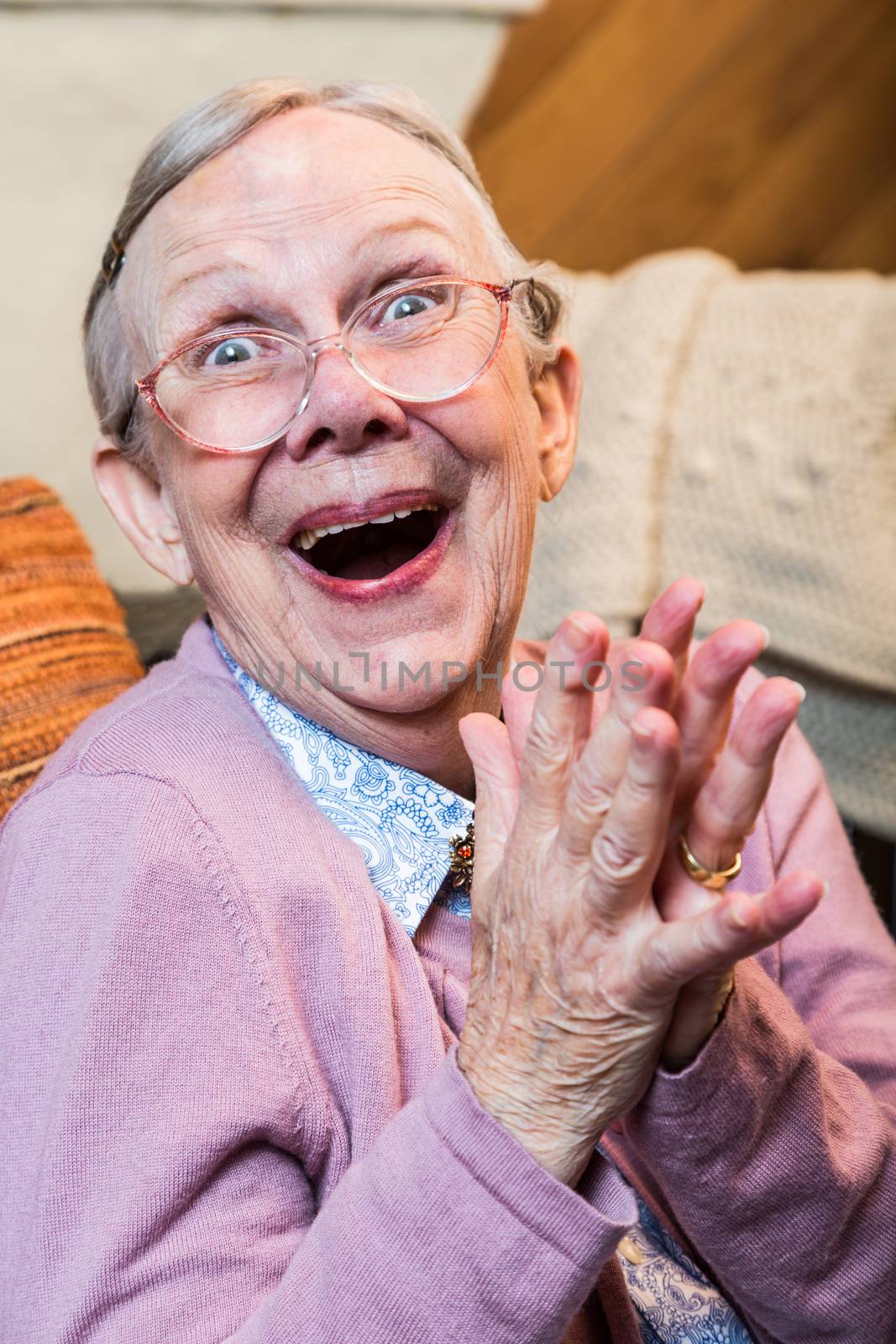 Joyful old woman in pink sweater with hands together