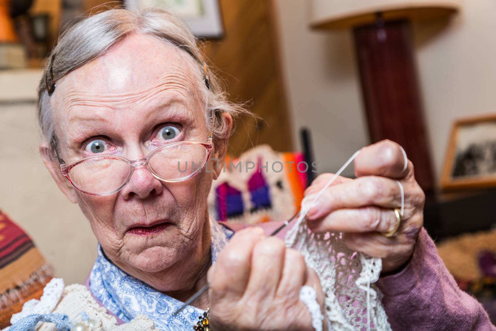 Elderly woman crocheting while looking at camera