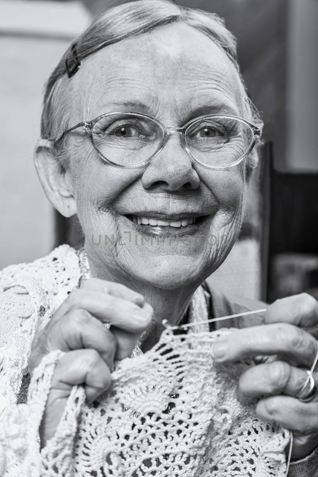 Smiling old woman with crochet looking at camera